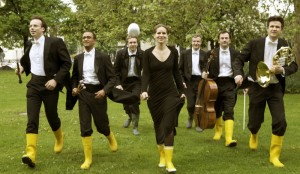 Musicians in yellow rubber boots carrying instruments