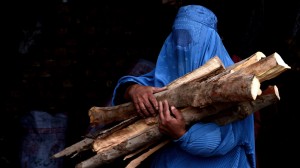 A burqa-clad Afghan woman carries chopped logs after buying them at a firewood yard in Herat. Photograph taken on February 23, 2015 (© AFP/Getty Images/A. Karimi)