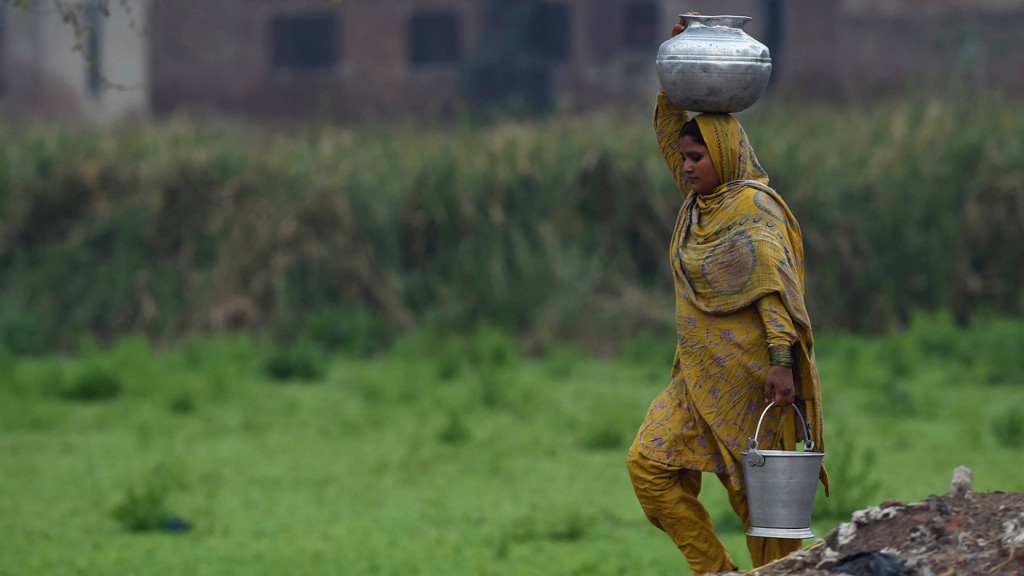 A Pakistani woman carries water pots make way for her home at a slum area © Arif Ali/AFP/Getty Images