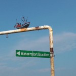 eine rostige Schilderstange mit einem Hinweisschild "Wassersport Brasilien"