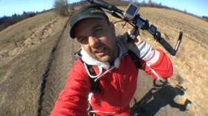 Michael Wigge trägt seinen Tretroller über einen schlammigen Feldweg